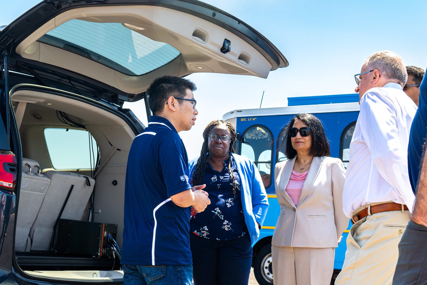 Lab members and Penn State President Neeli Bendapudi at the open rear of the automated vehicle on the test track