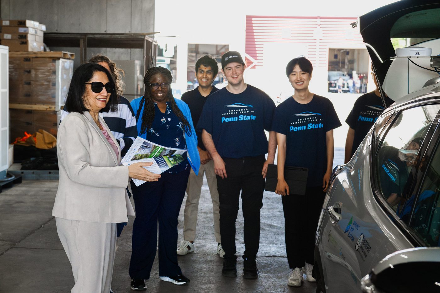 President Bendapudi with student researchers beside the automated vehicle