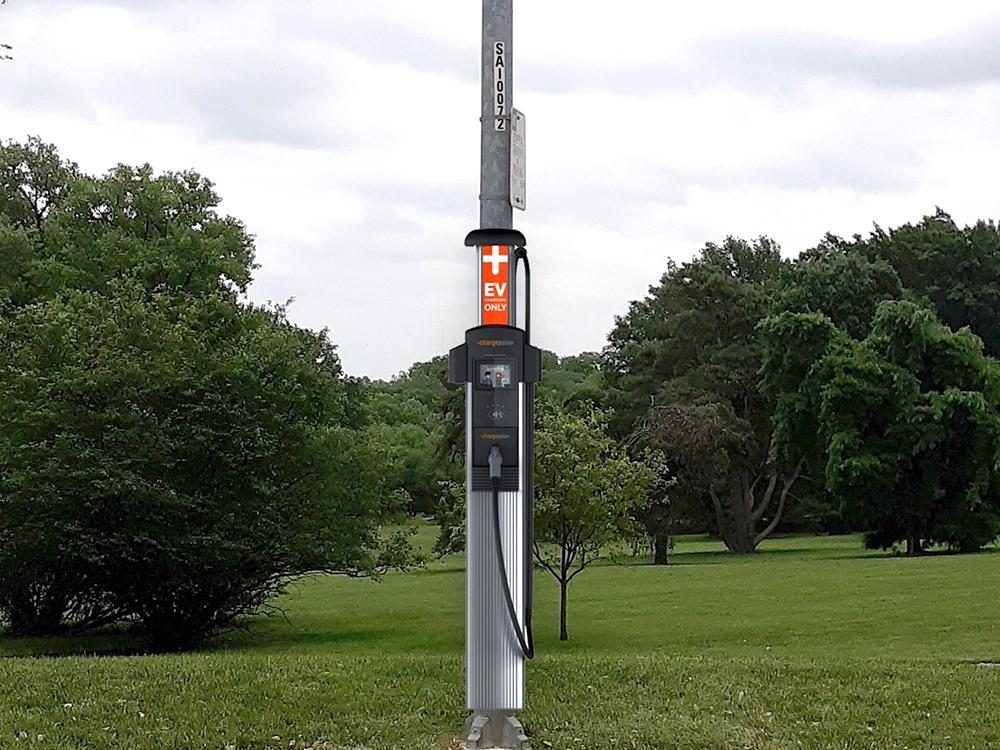 An electric vehicle charging from a streetlight-mounted charger in Kansas City