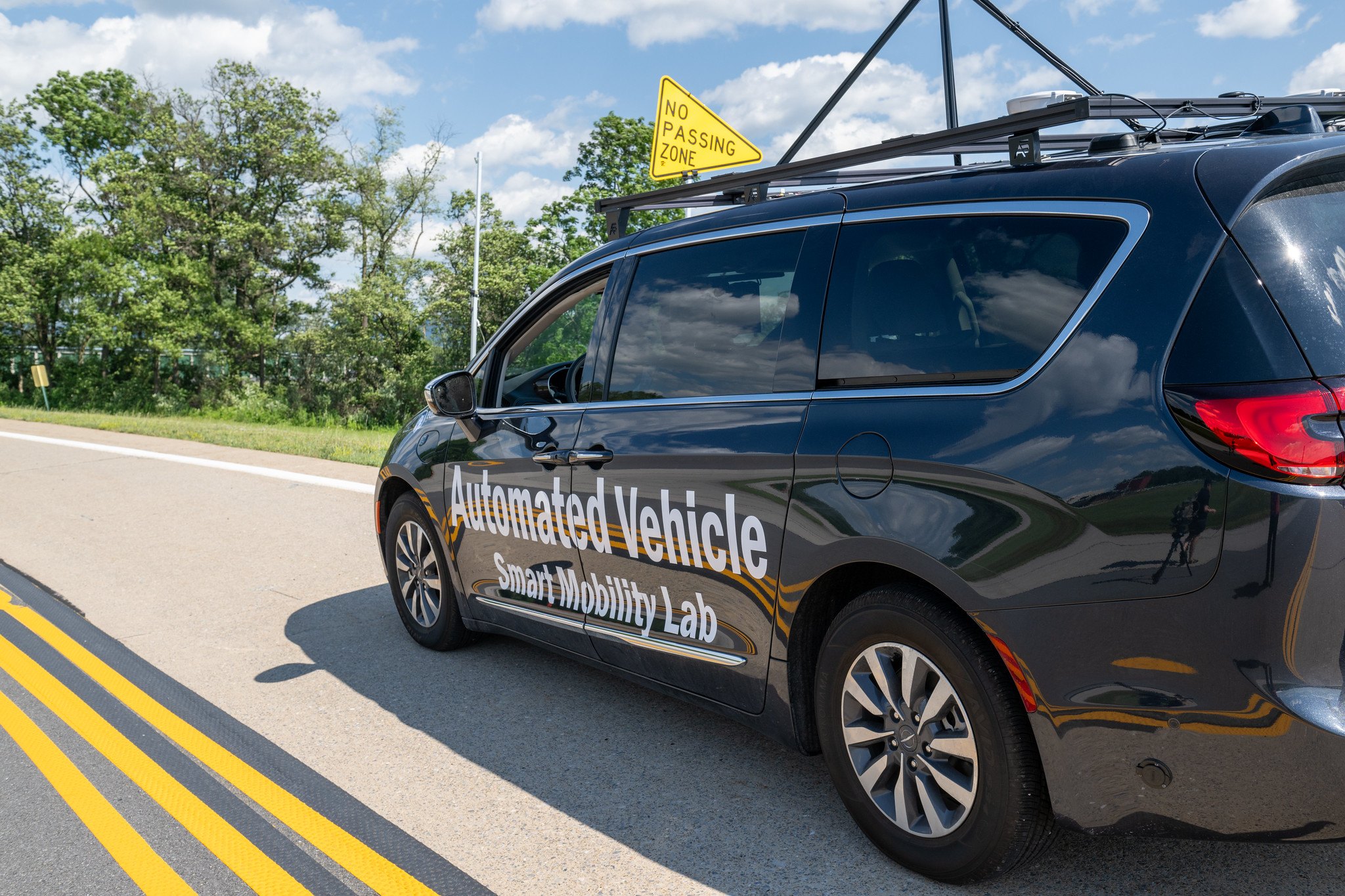The lab’s wrapped automated vehicle on the LTI test track beside a no-passing-zone sign